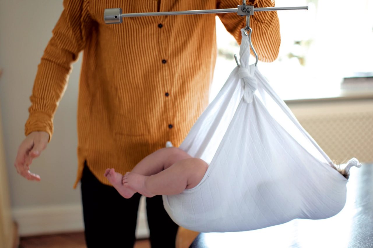 baby lying in a sling to be weighed